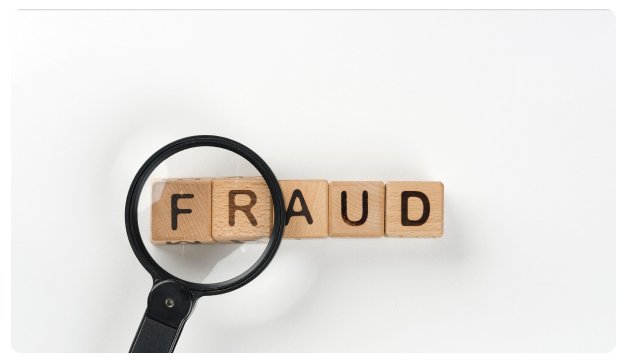 Magnifying glass over wooden blocks spelling the word 'Fraud'